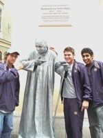 Santiago Montoya, Stephen Bass, and Sheeva Parbhu posing with a man posing as a statue in the streets of Salzburg.