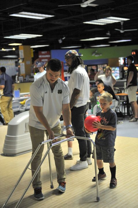 Junior safety Drew Recker helps a child with his bowling game at Strikes 'N' Spares Bowling Alley during an Charity Event Sunday.