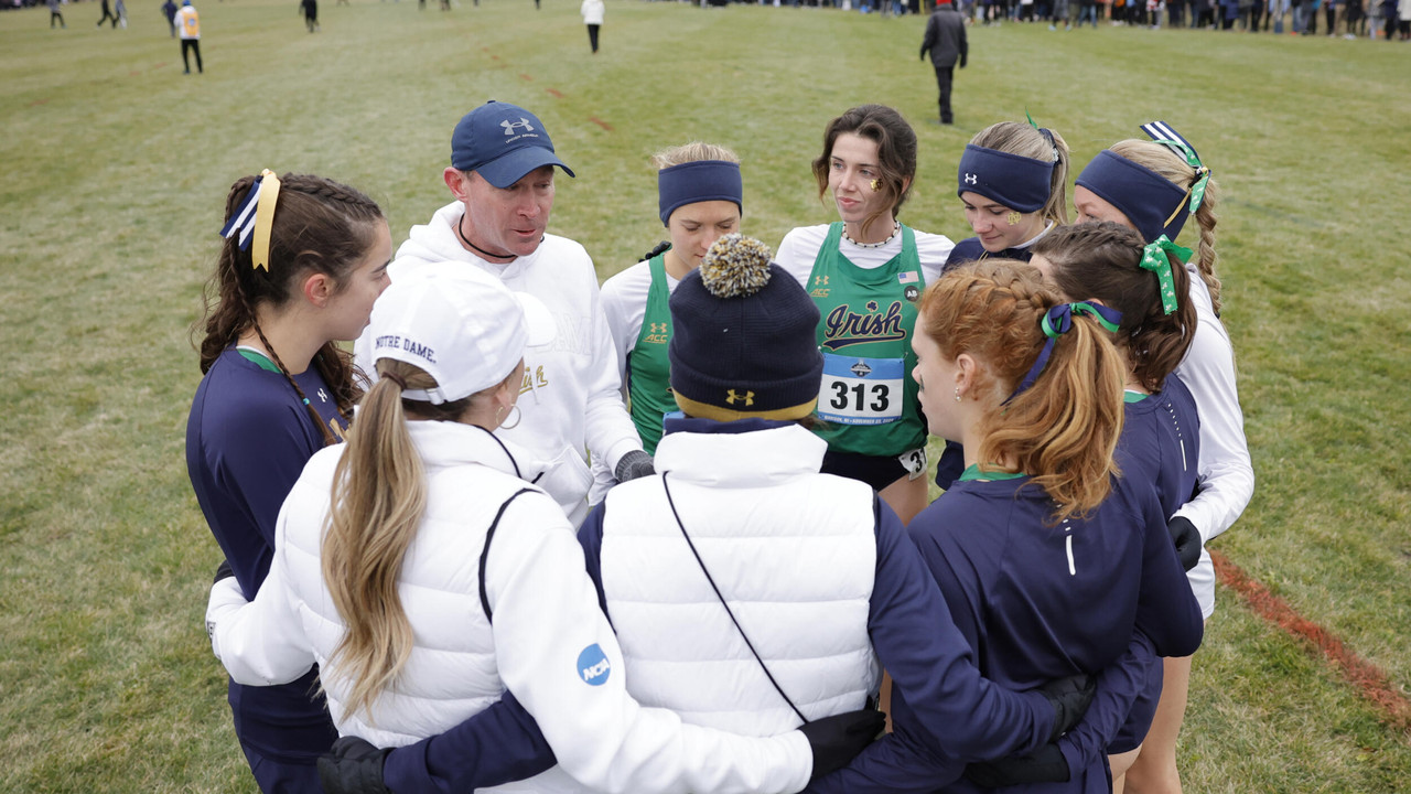 The women's cross country team huddles and listens to Coach Matt Sparks