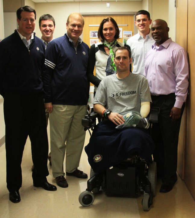 (left to right): Monogram Club president Dick Nussbaum ('74, '77 baseball), first vice president Haley Scott DeMaria ('95, swimming), intern Mike Sullivan ('09, student manager) and manager for Monogram/football relations Reggie Brooks ('93, football) visit with a wounded soldier at Walter Reed National Military Medical Center.