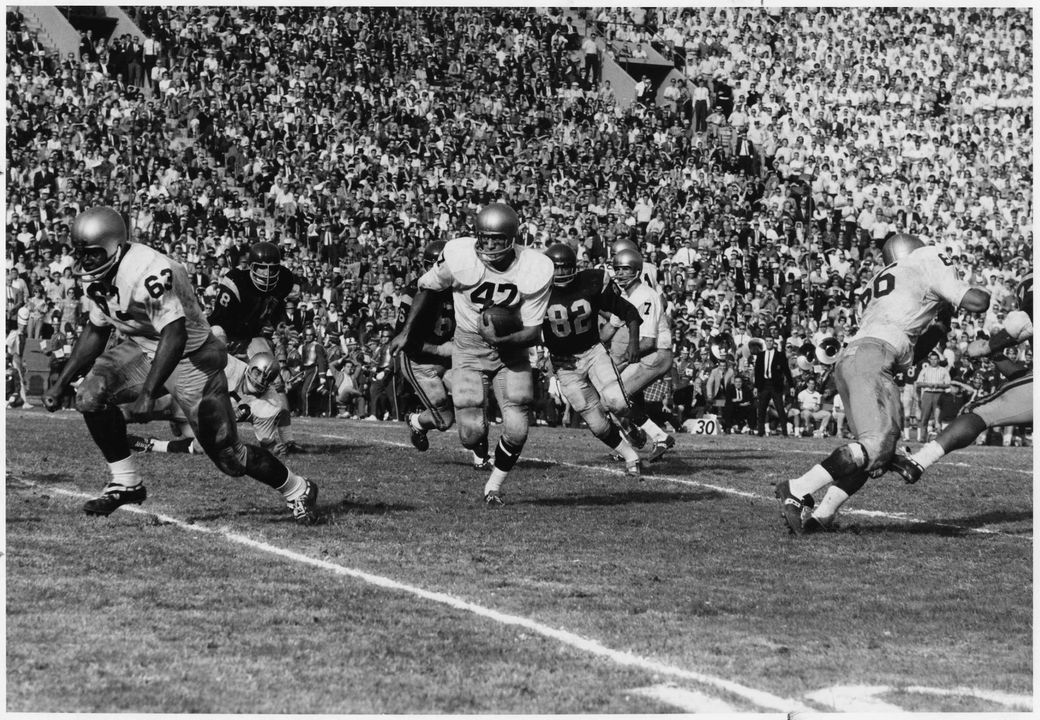 Player Nick Eddy (#47) running with the ball while Dick Arrington (#63) and John Atamian (#66) block.