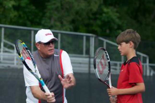 Men's Tennis head Coach Bobby Bayliss instructs the next generation of tennis player how to hit a forehand ball.