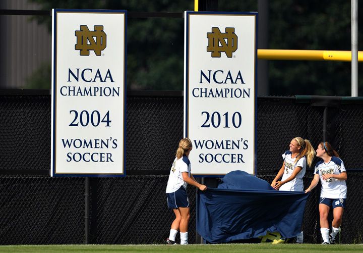 Prior to Friday's season opener, Notre Dame senior tri-captains Jessica Schuveiller (left), Melissa Henderson (center) and Courtney Barg (right) unveil the 2010 NCAA national championship banner that now hangs at Alumni Stadium.