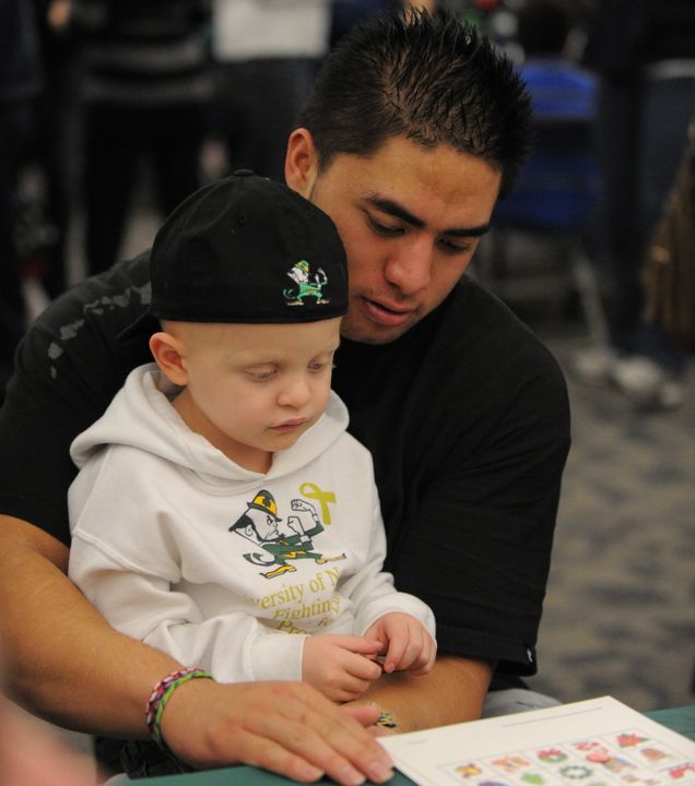 Senior linebacker Manti Te'o helps a young patient read at the Hematology/Oncology Pediatric Christmas Party.